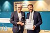 – Matthias Priwitzer (l.), Leitung Kommunikation & Marketing der BayernLB, übergibt die Auszeichnung zum Bayerischen Journalisten des Jahres 2025 an Johannes Reichart.